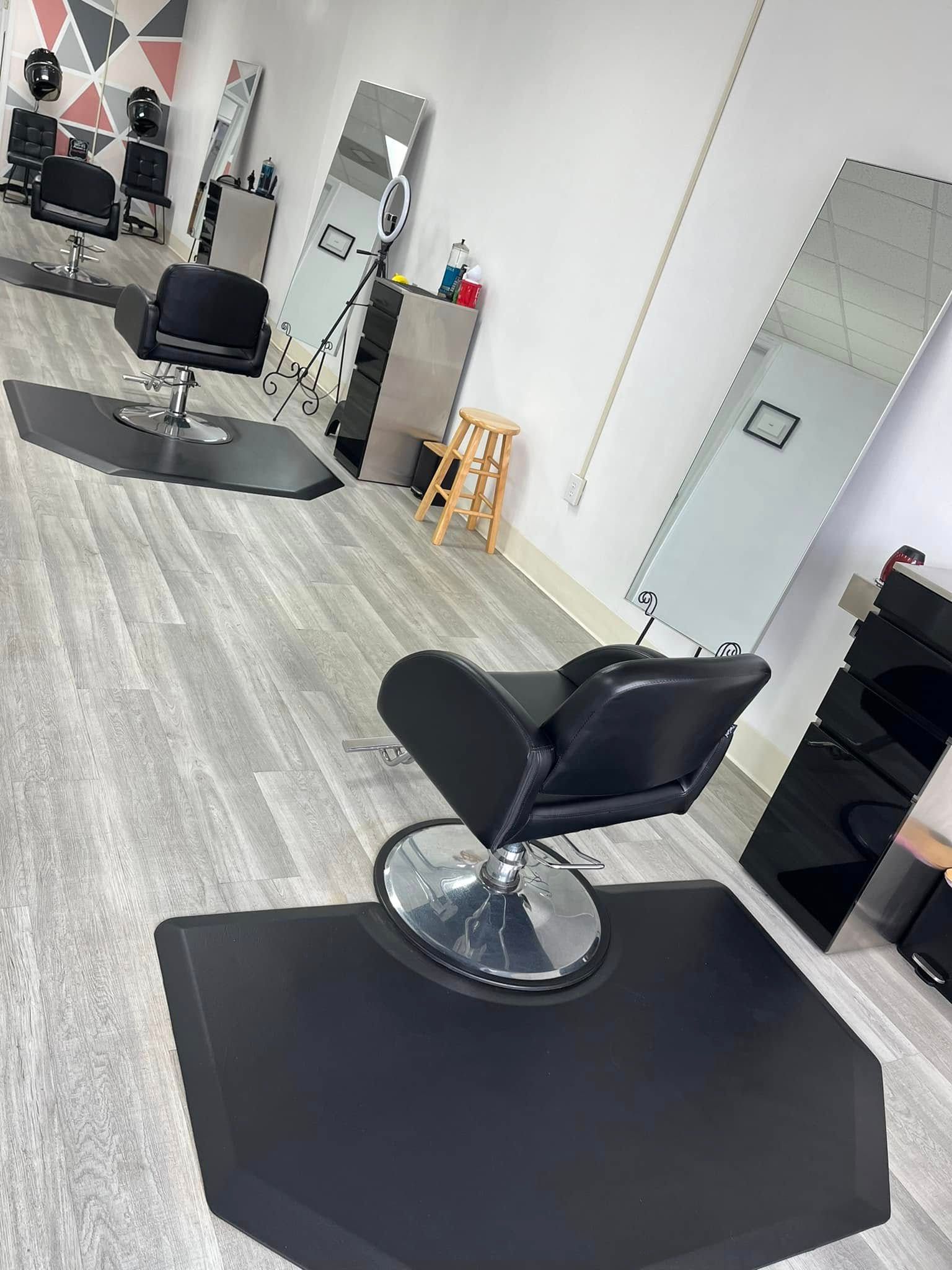 Hair salon interior with black chairs, mirrors, and flooring.