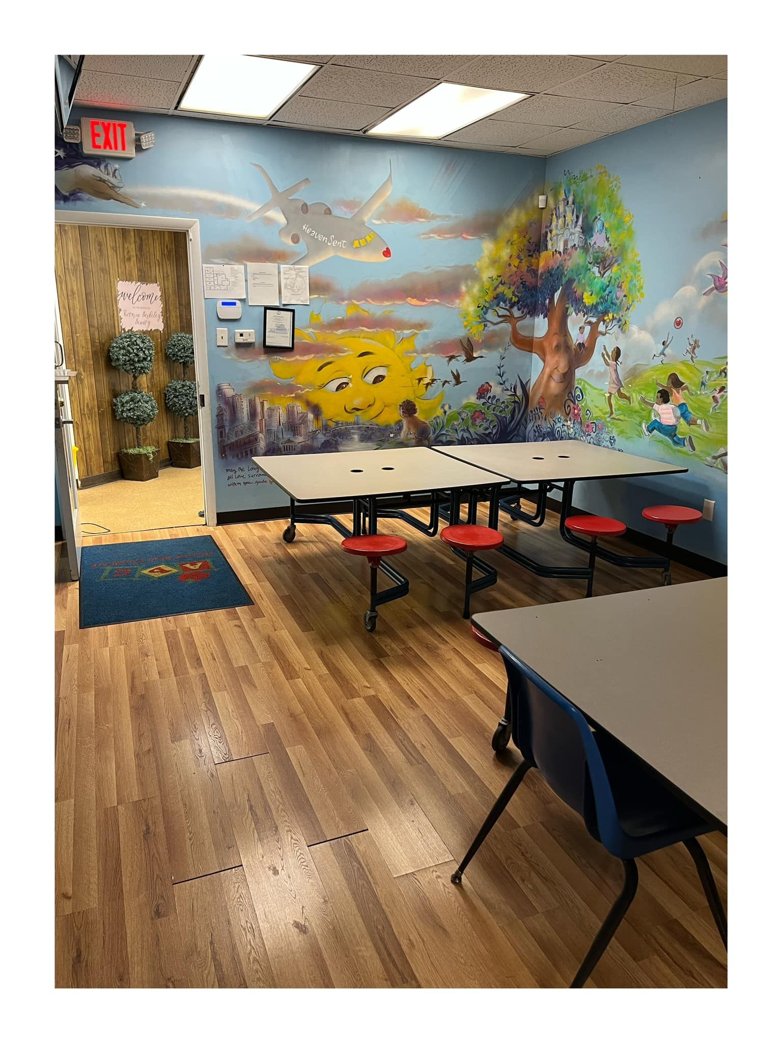 Classroom with painted mural on wall, desks and red stools.
