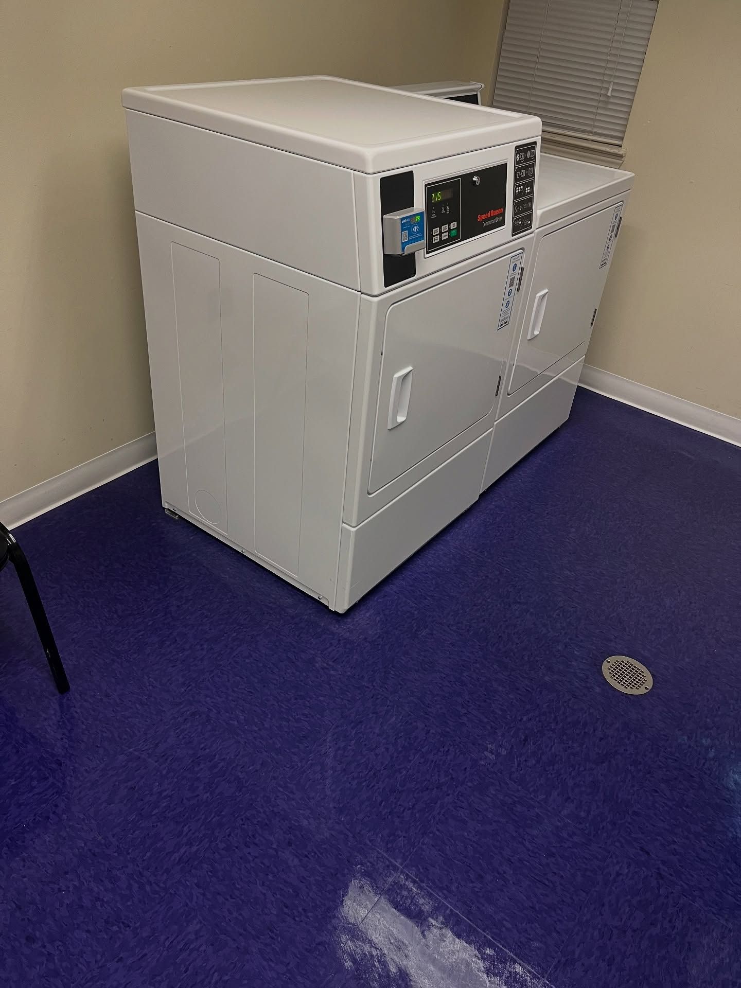 White commercial dryer in a room with blue flooring.