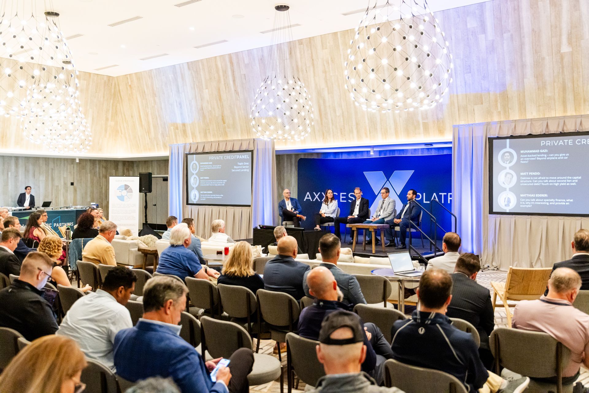 A group of people are sitting in chairs in front of a stage at a conference.