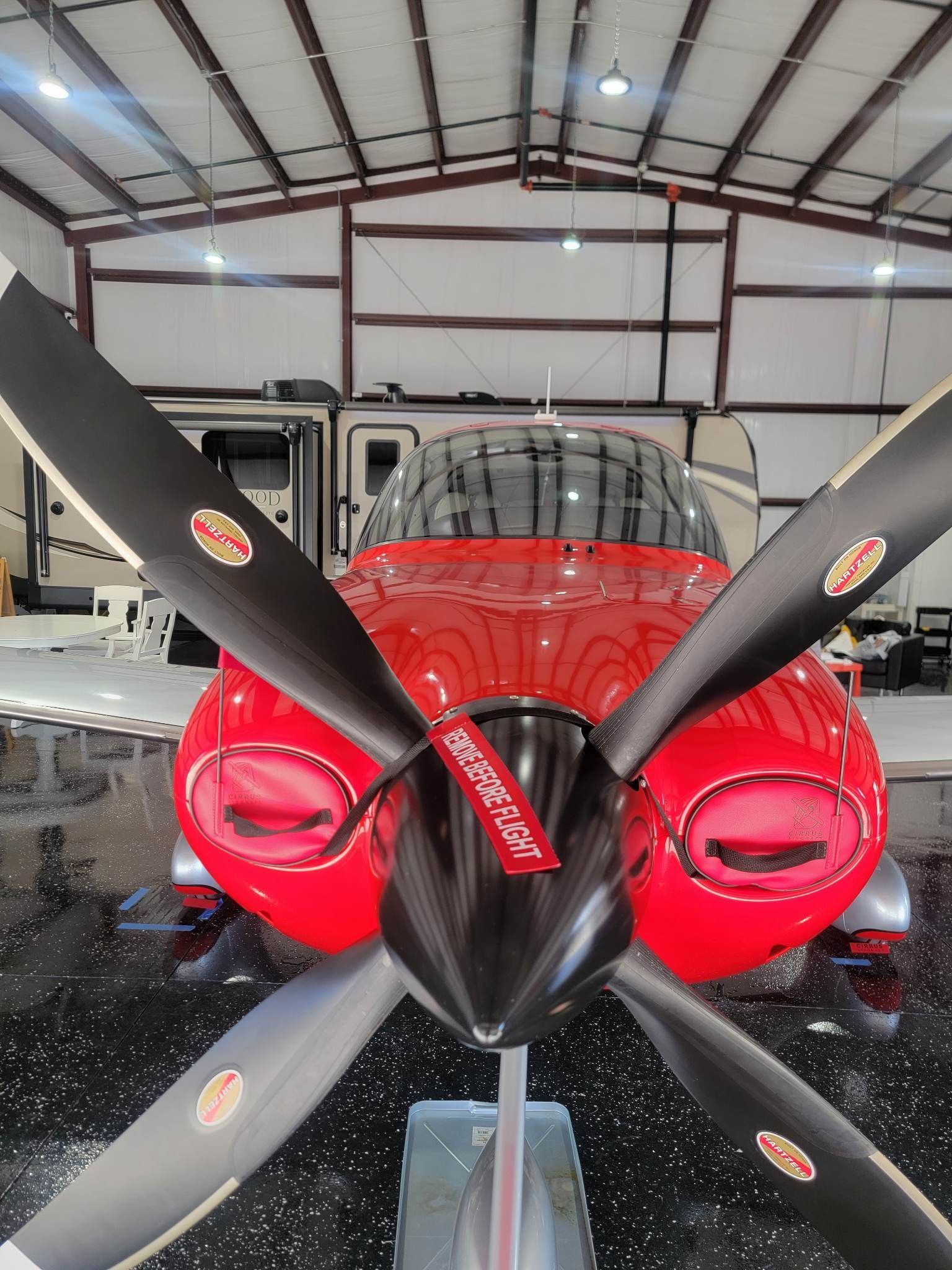 A red propeller plane is parked in a hangar