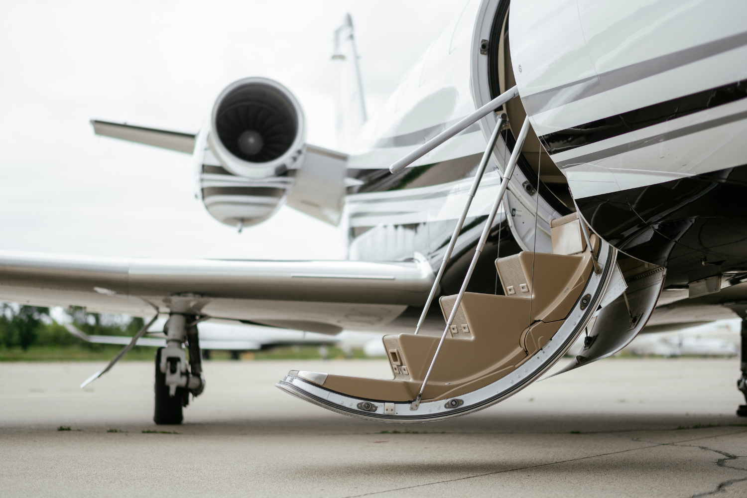 A private jet is parked on the tarmac with its stairs open.