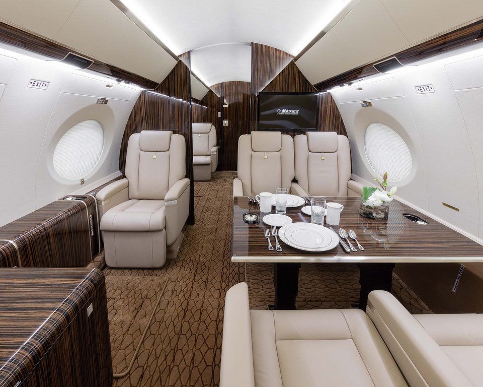 The inside of a private jet with a table and chairs.