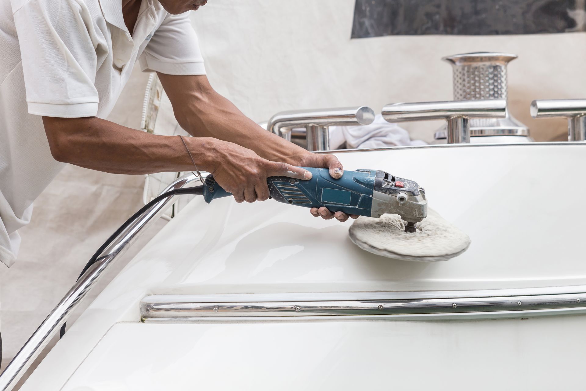 A man is polishing a boat with a machine.