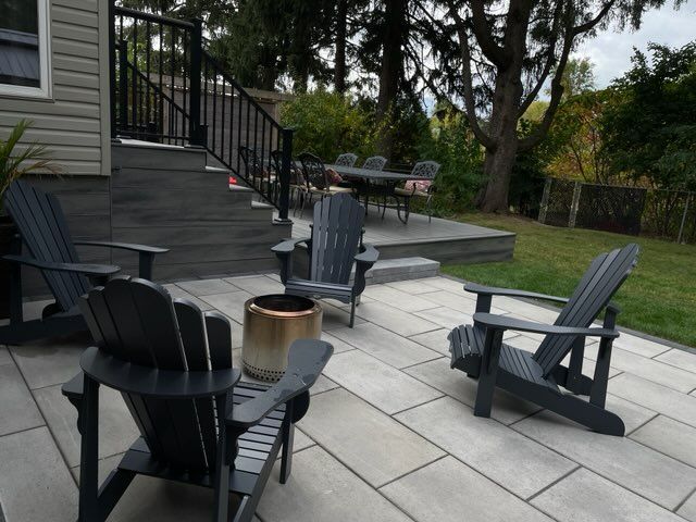 Outdoor patio with Adirondack chairs, fire pit, steps, and dining set in a yard.