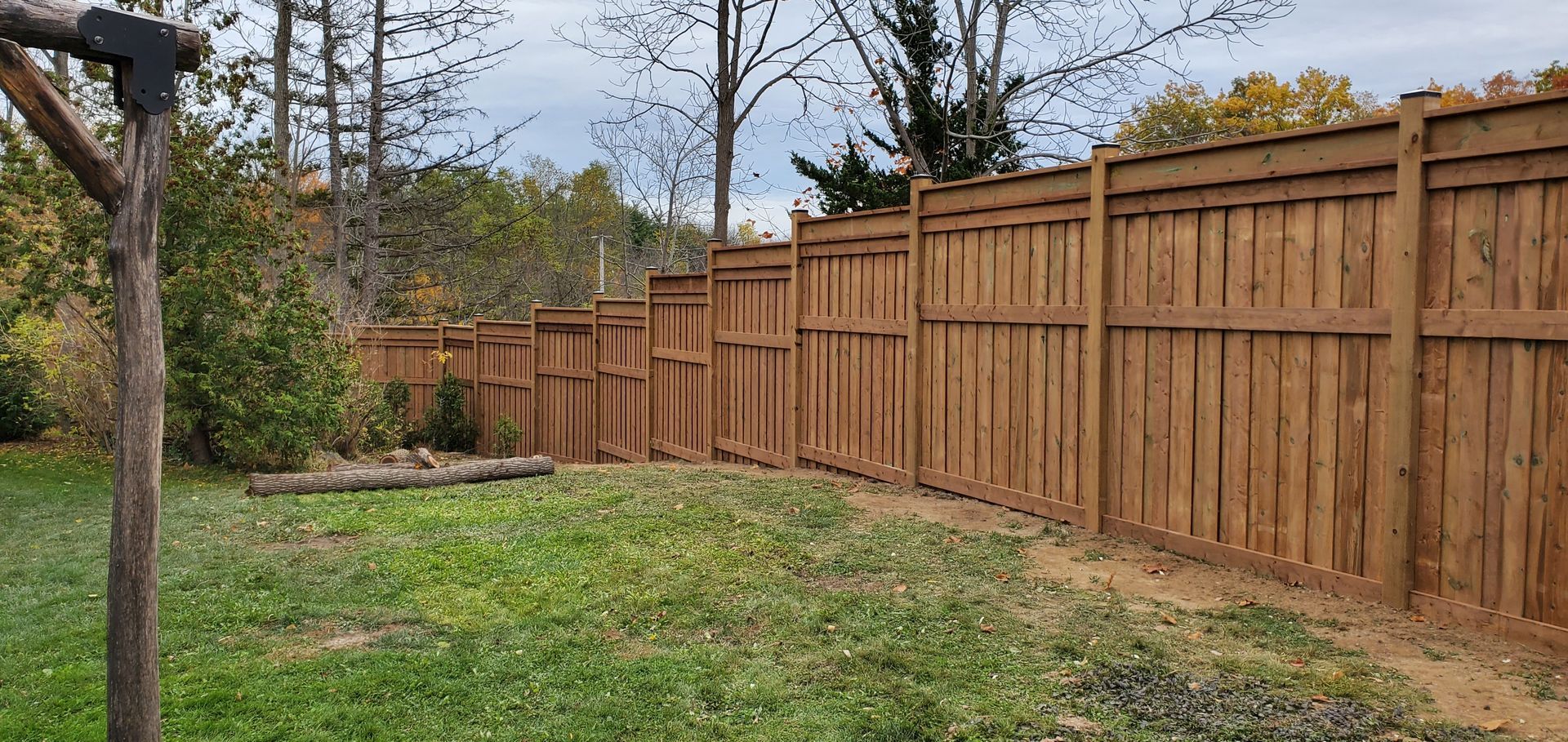 A wooden fence surrounds a lush green yard.