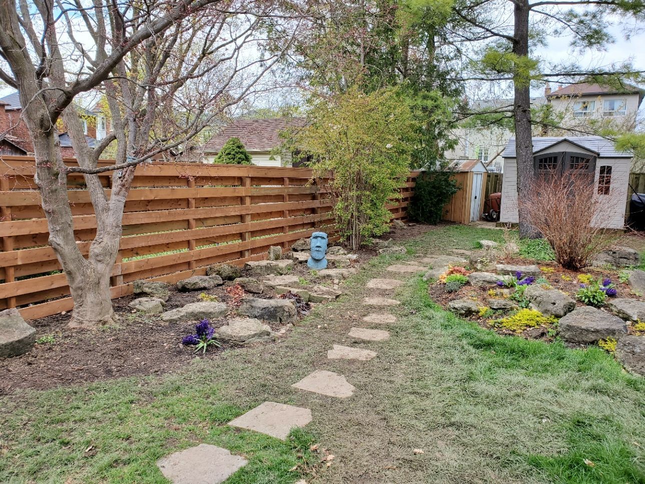 A backyard with a wooden fence and a stone path.