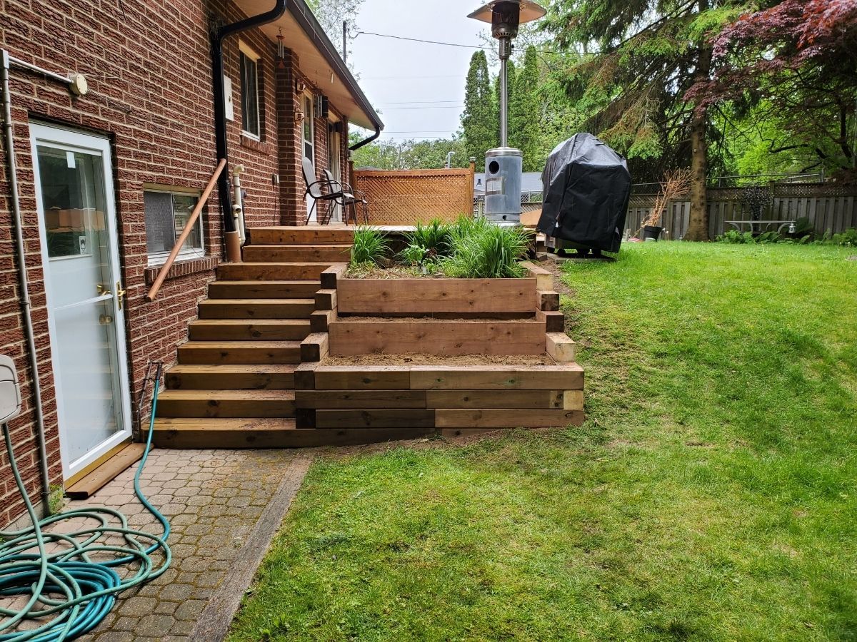 a brick house with a wooden deck and stairs in the backyard .