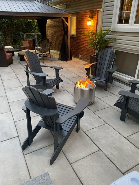 a patio with chairs and a fire pit in the middle