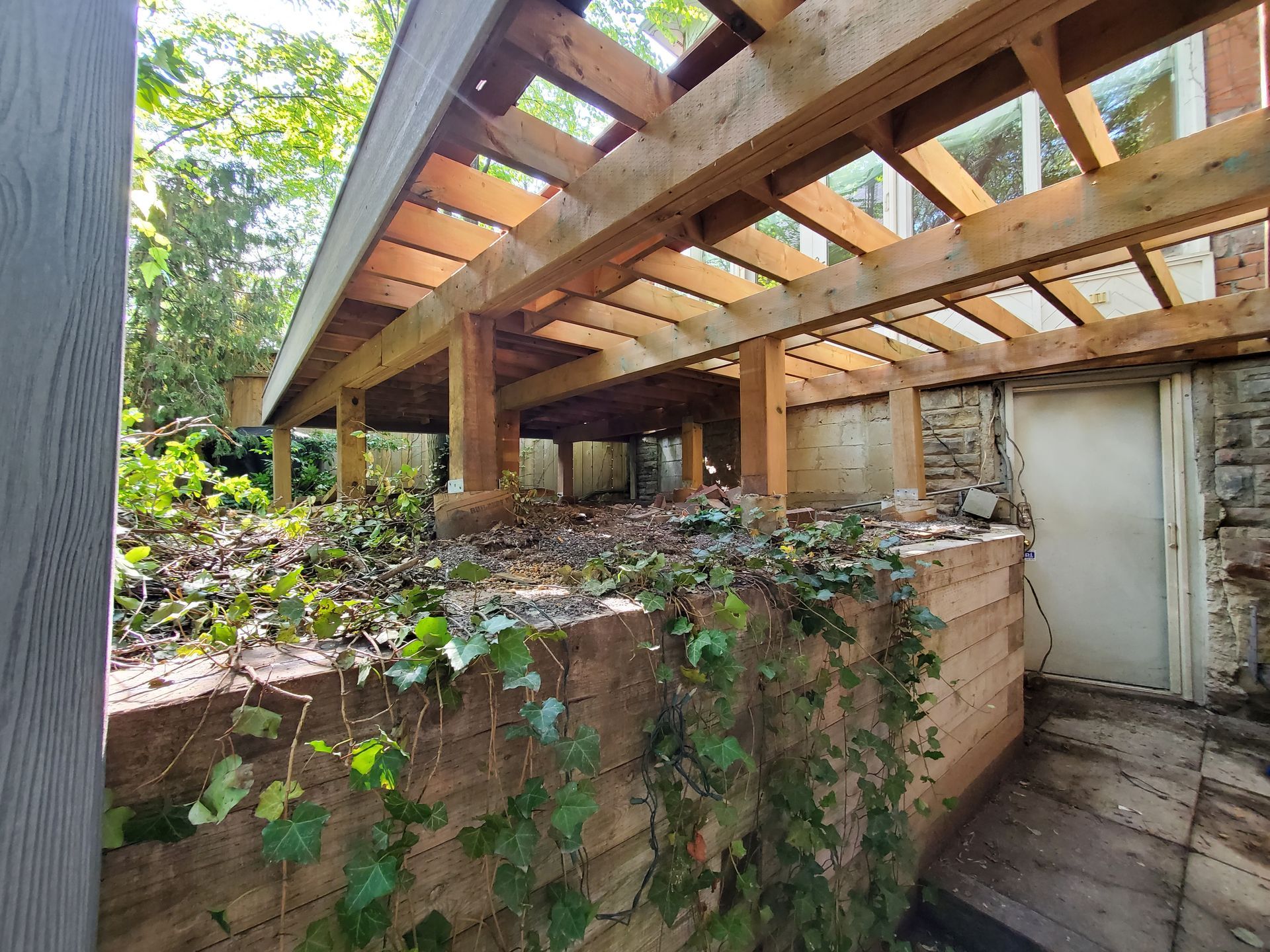 a wooden pergola is sitting on top of a stone wall .