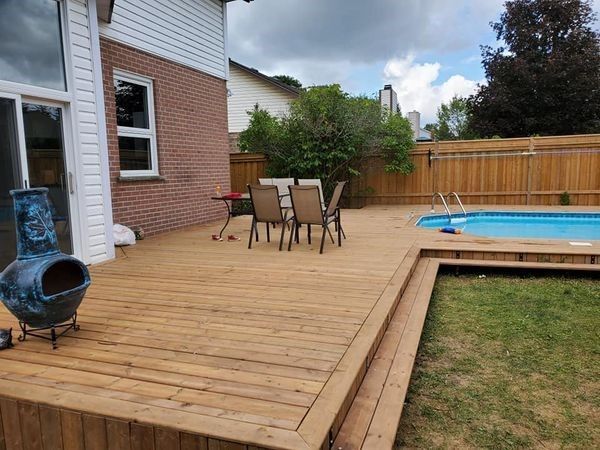 a wooden deck with a table and chairs next to a swimming pool .