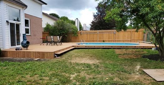 a wooden deck with a swimming pool in the backyard of a house .