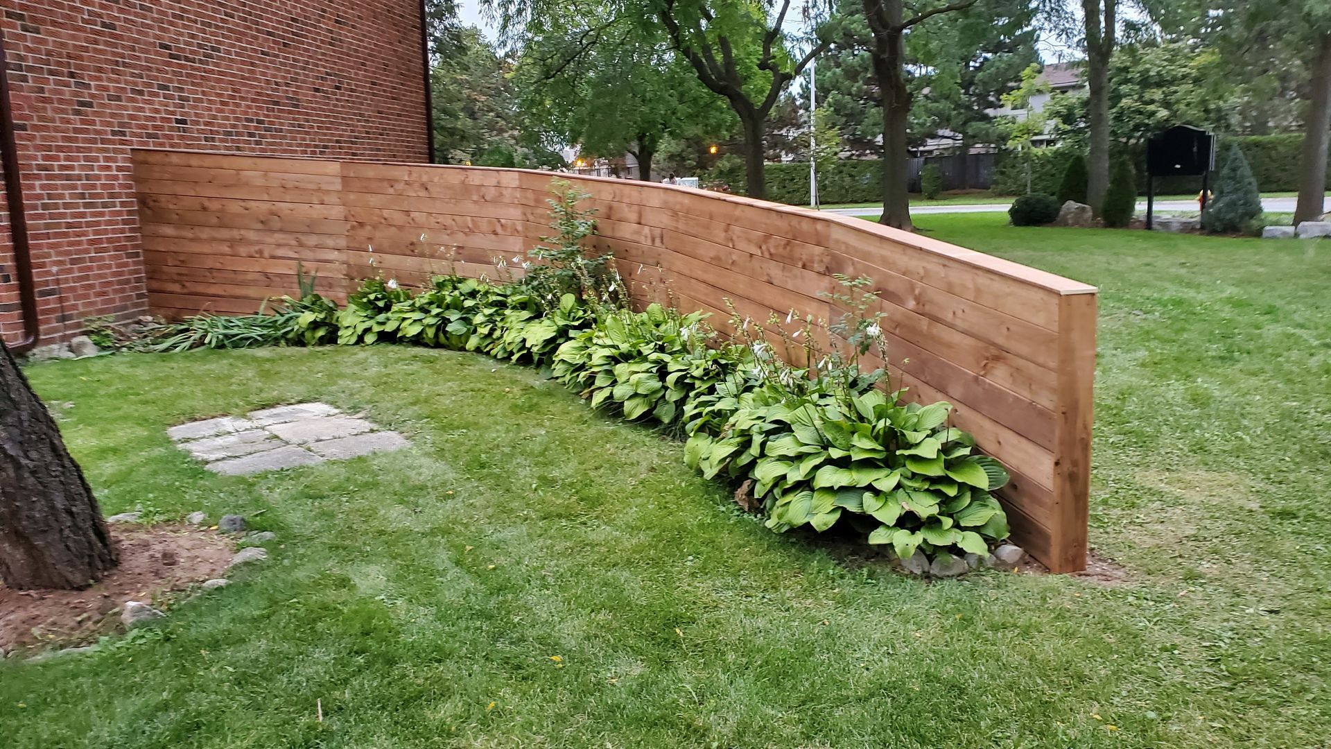 a wooden fence is surrounded by plants in a yard .