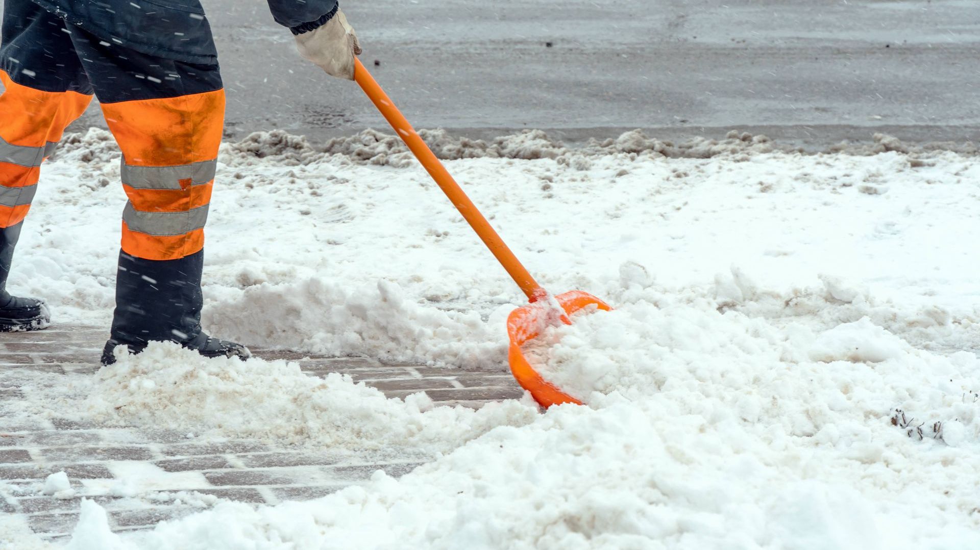 a man wearing orange and black pants is shoveling snow