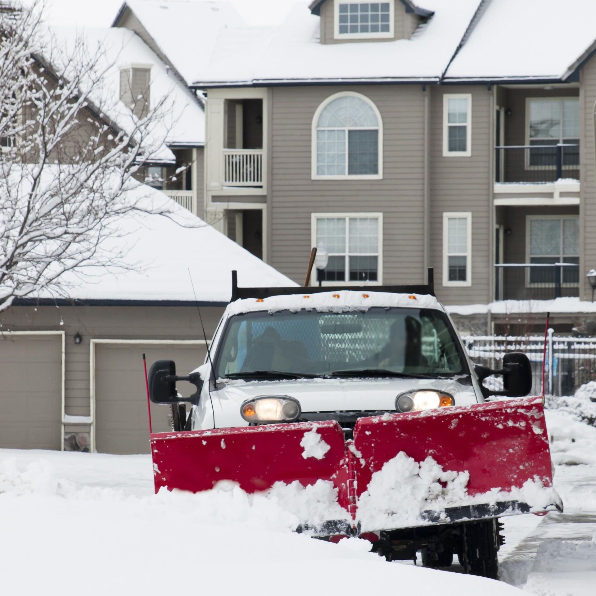 a snow plow is clearing snow in front of a house