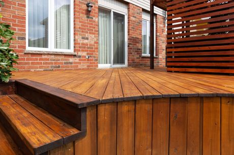 a wooden deck in front of a brick house