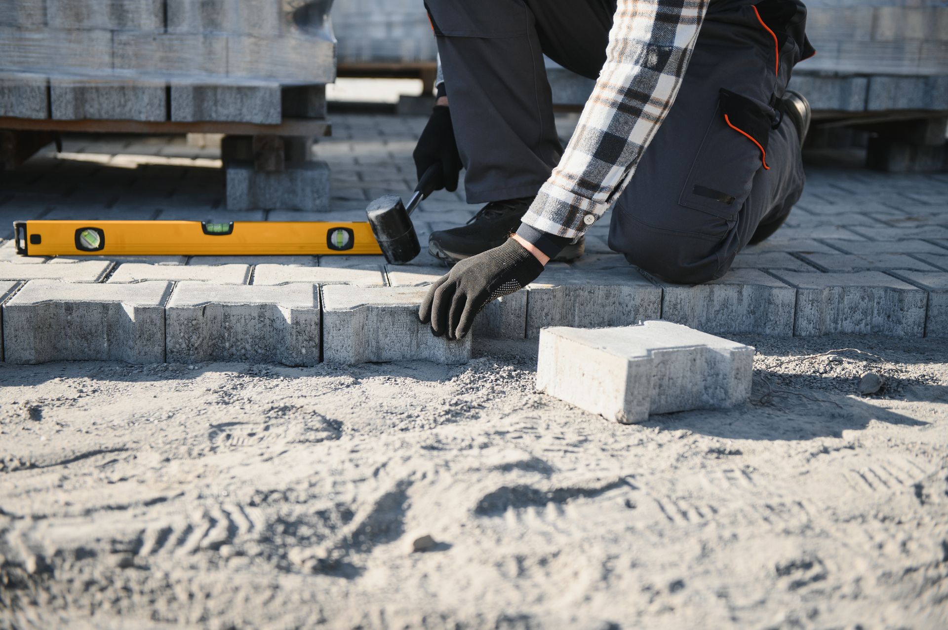 A man is laying bricks on a sidewalk.