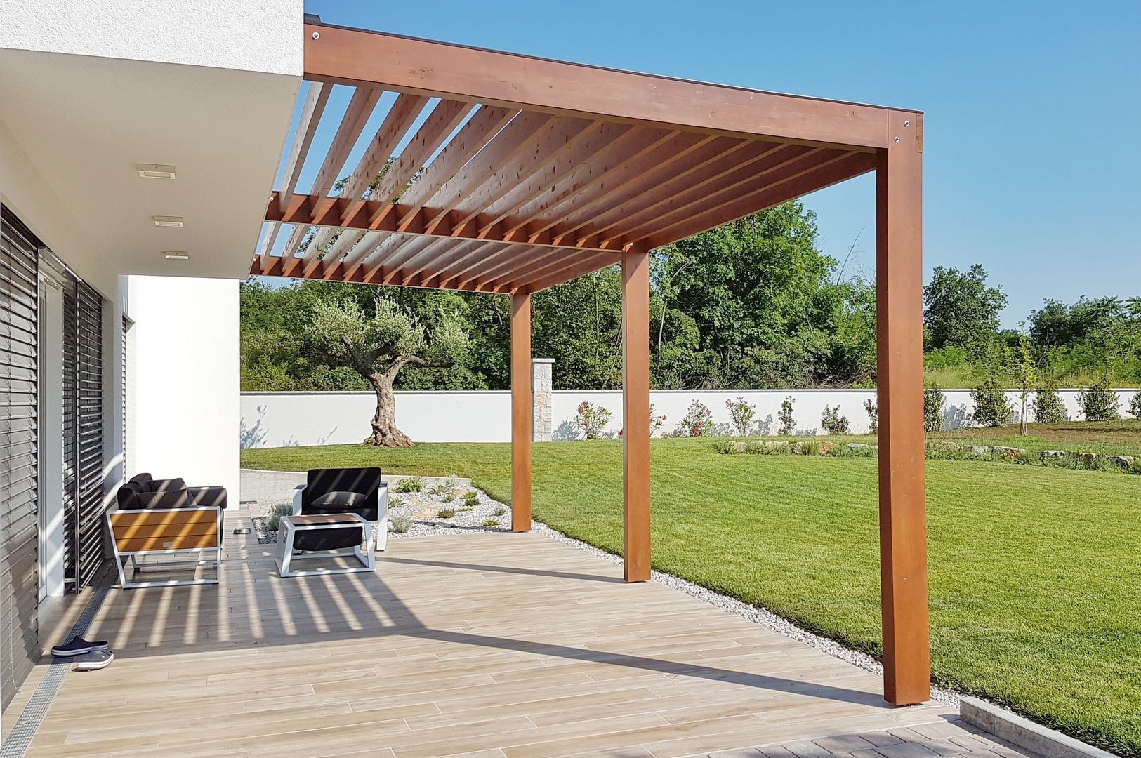 A wooden pergola is sitting on top of a patio next to a house.