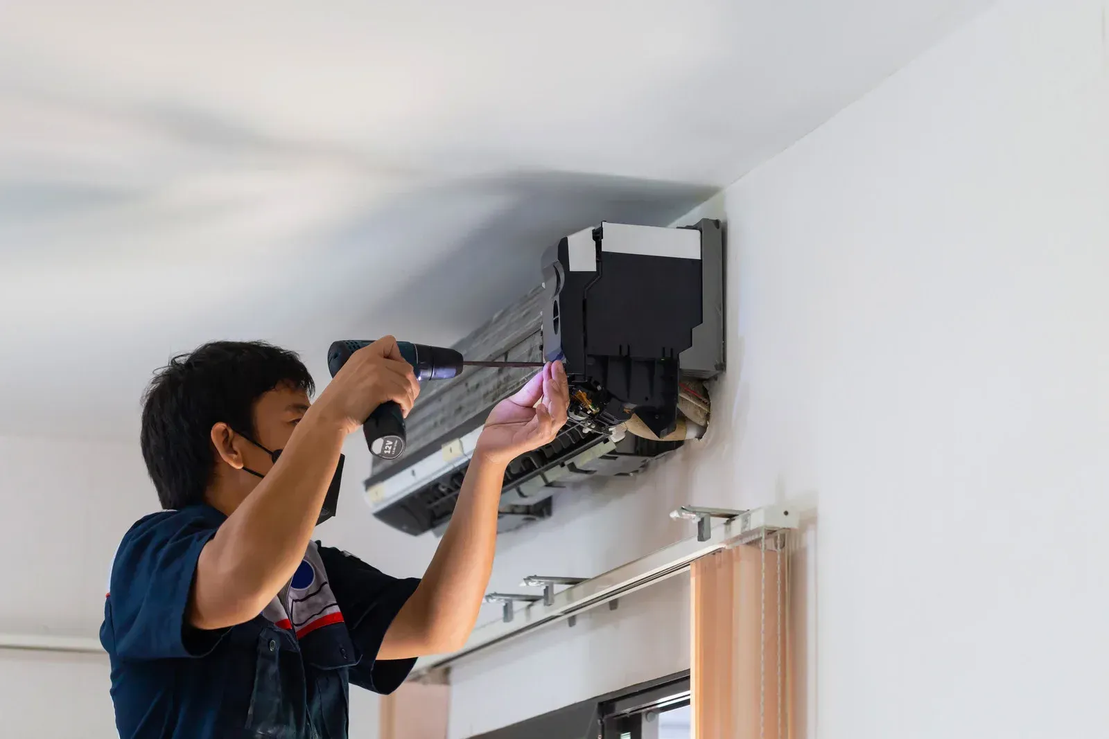 A man is working on an air conditioner in a living room.