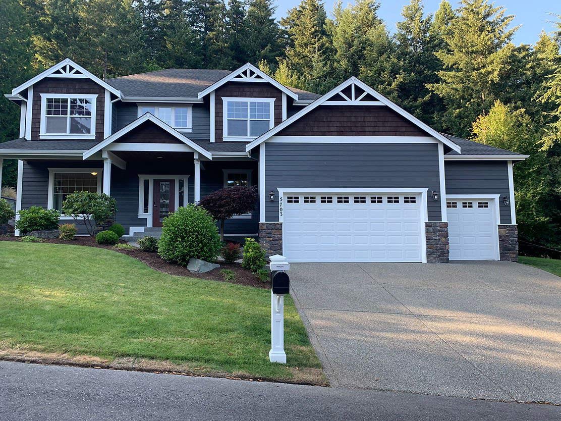 Large craftsman-style home with dark blue exterior paint, white trim, and well-maintained landscaping.