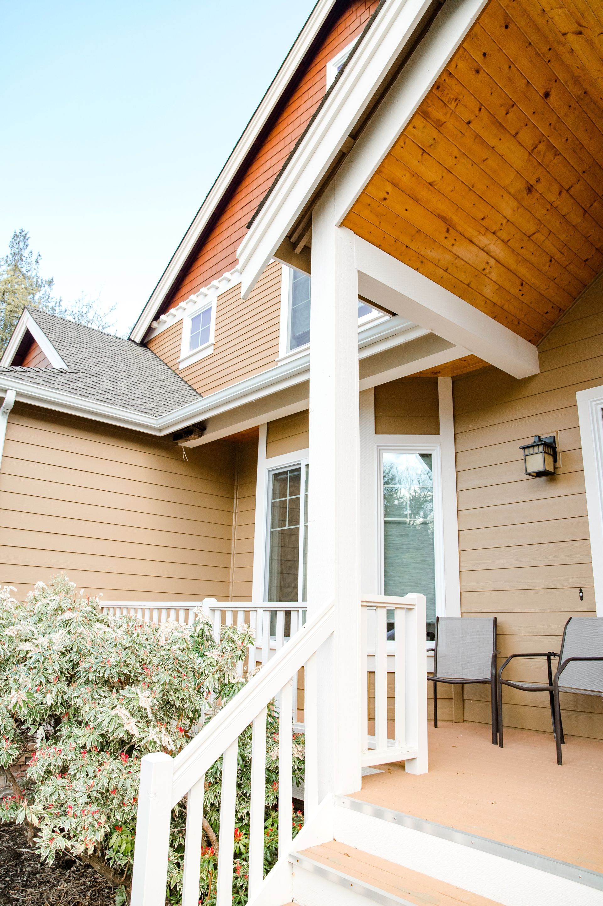 A porch with a wooden ceiling and chairs on it