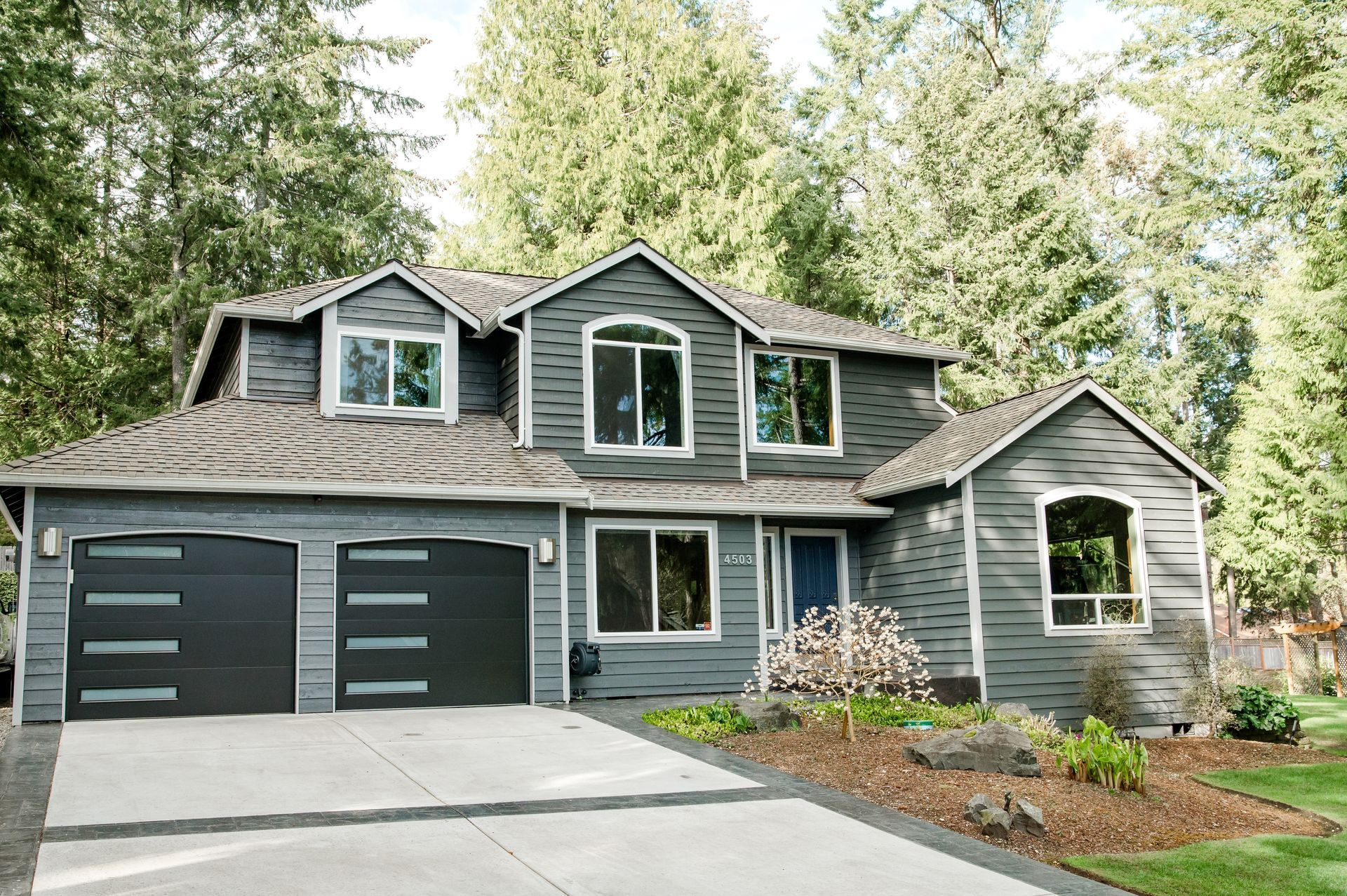 A large gray house with a black garage door
