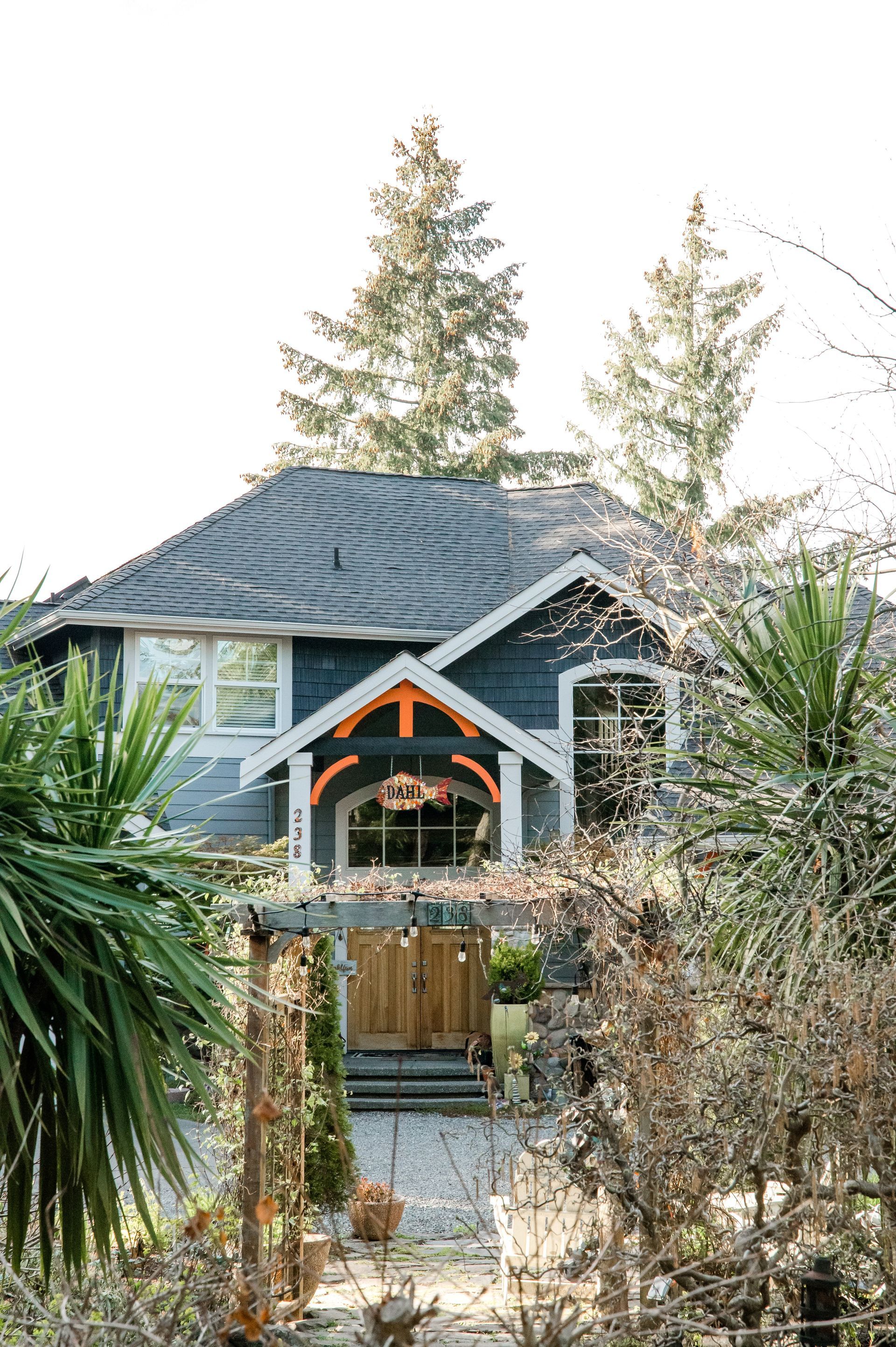 A small house is surrounded by palm trees and bushes.