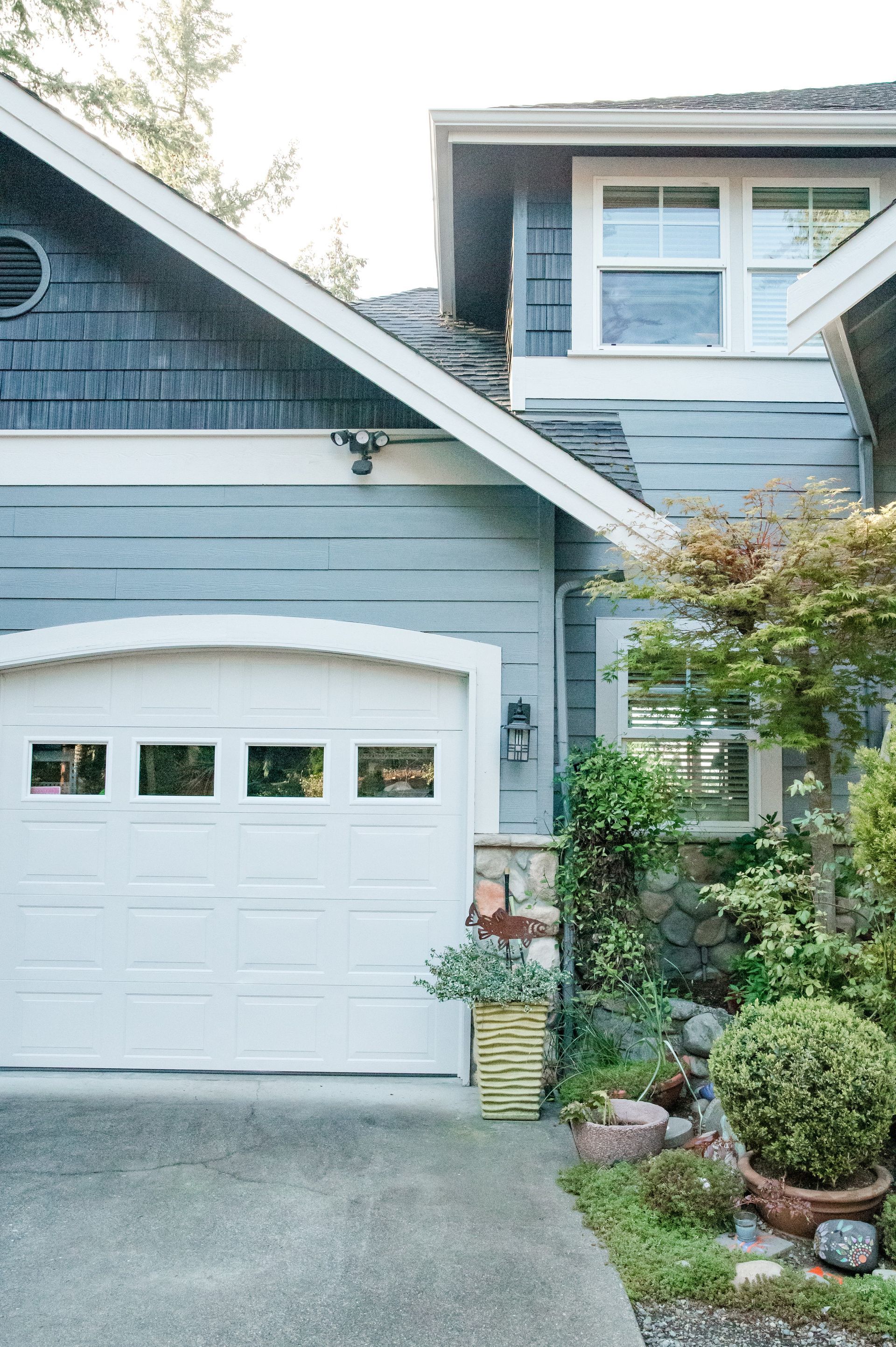 A blue house with a white garage door and a driveway.