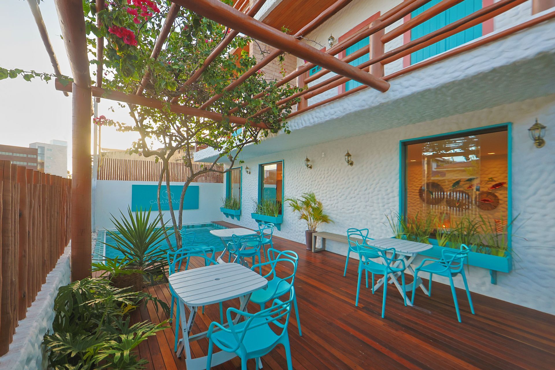 Um deck de madeira com mesas e cadeiras em frente a um prédio.