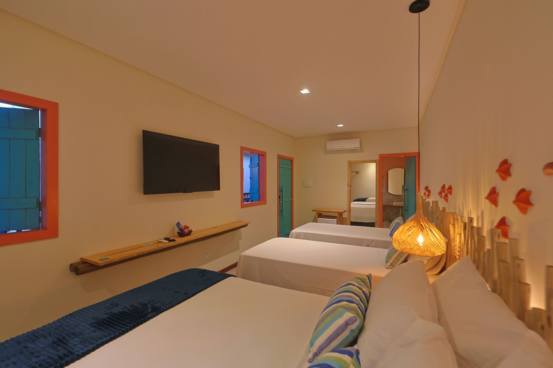 Um quarto de hotel com três camas e uma TV de tela plana.