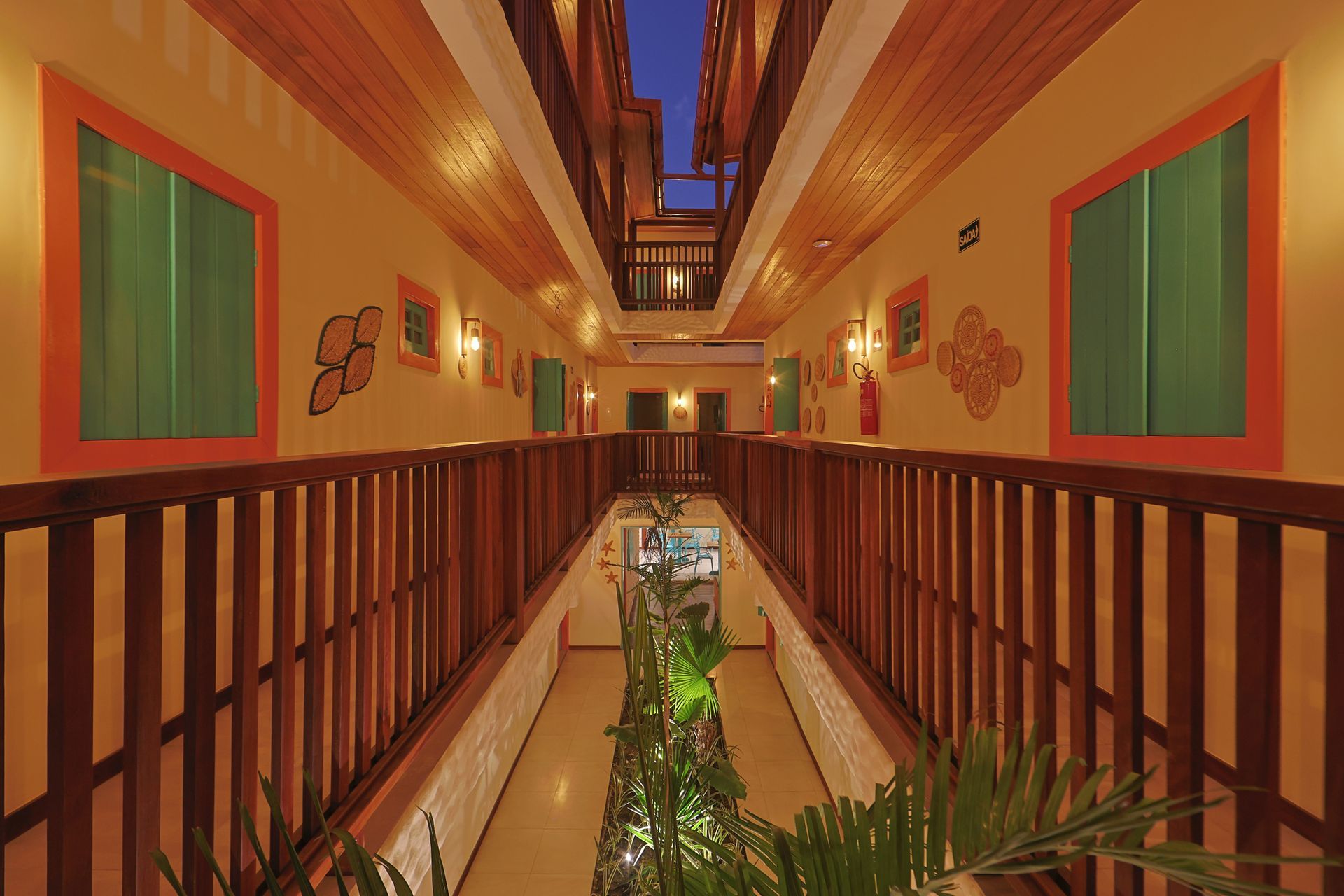 Um longo corredor com corrimão de madeira e uma varanda em um hotel.