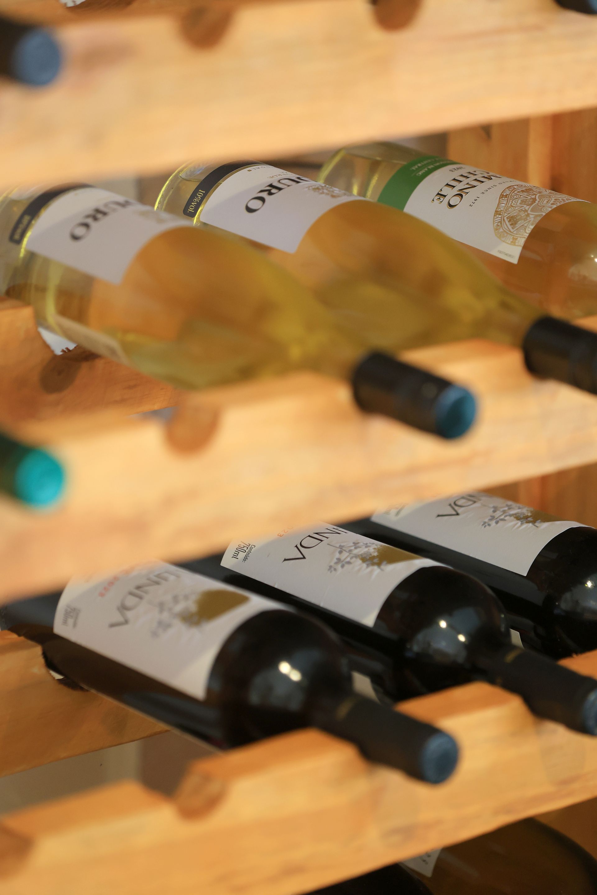 Várias garrafas de vinho estão alinhadas em uma prateleira de madeira