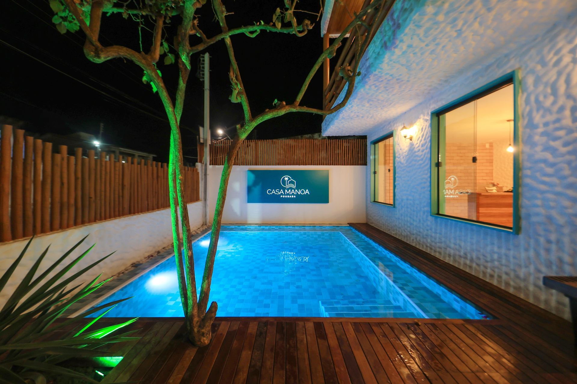 Uma grande piscina é cercada por um deck de madeira e uma cerca.