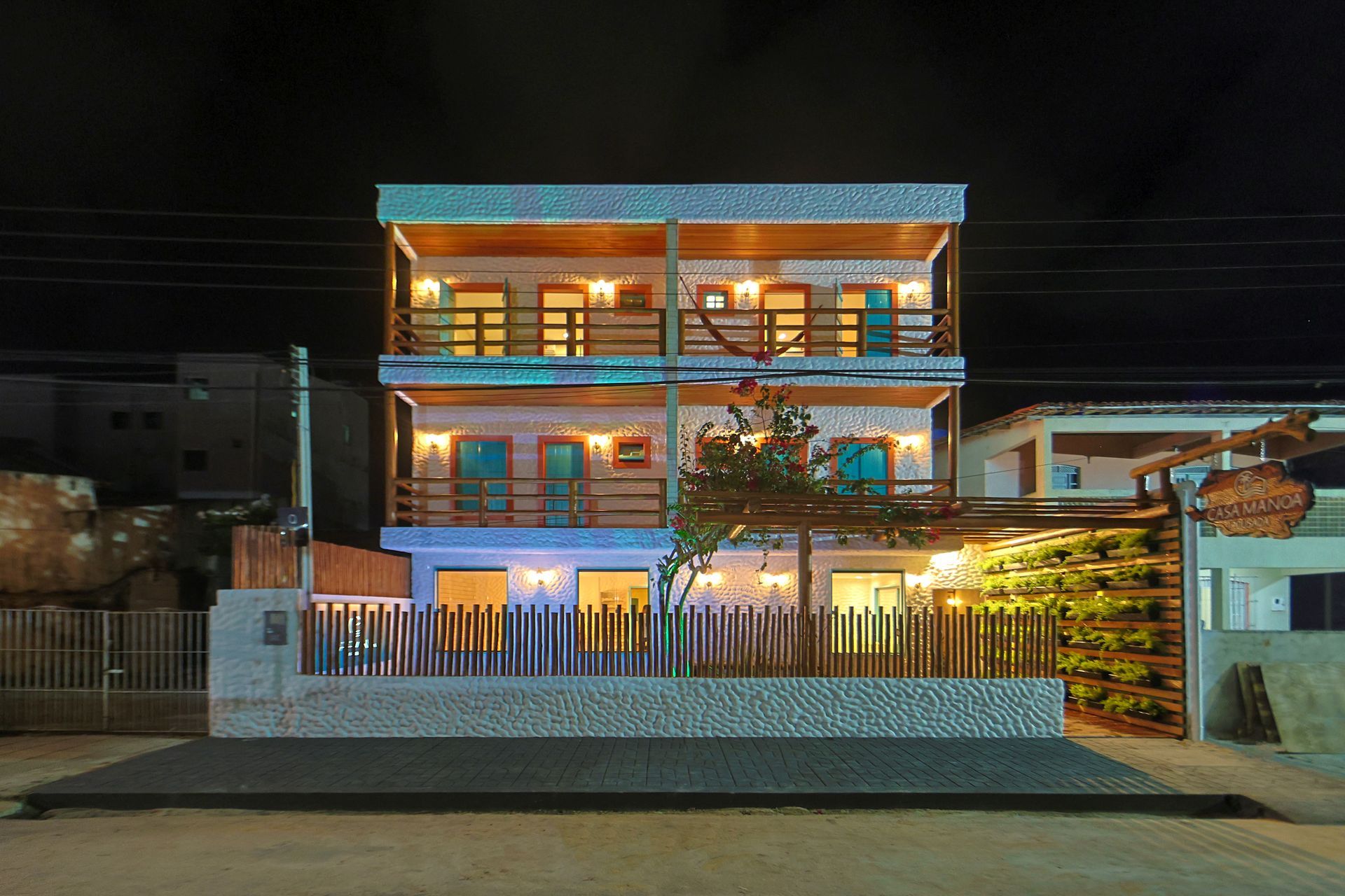 Um grande edifício com uma cerca ao redor é iluminado à noite.