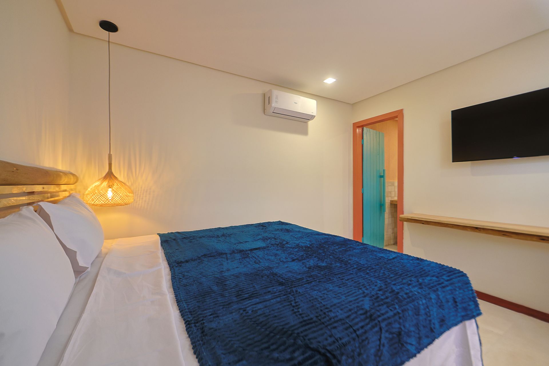 Um quarto com cama, televisão e ar condicionado.