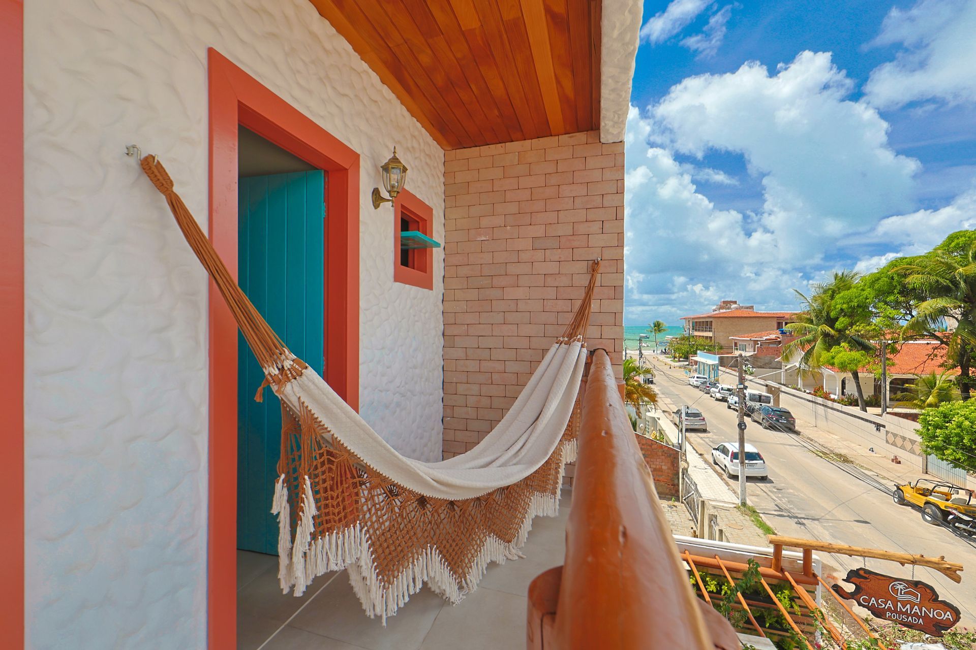 Uma rede está pendurada em uma sacada com vista para uma rua.