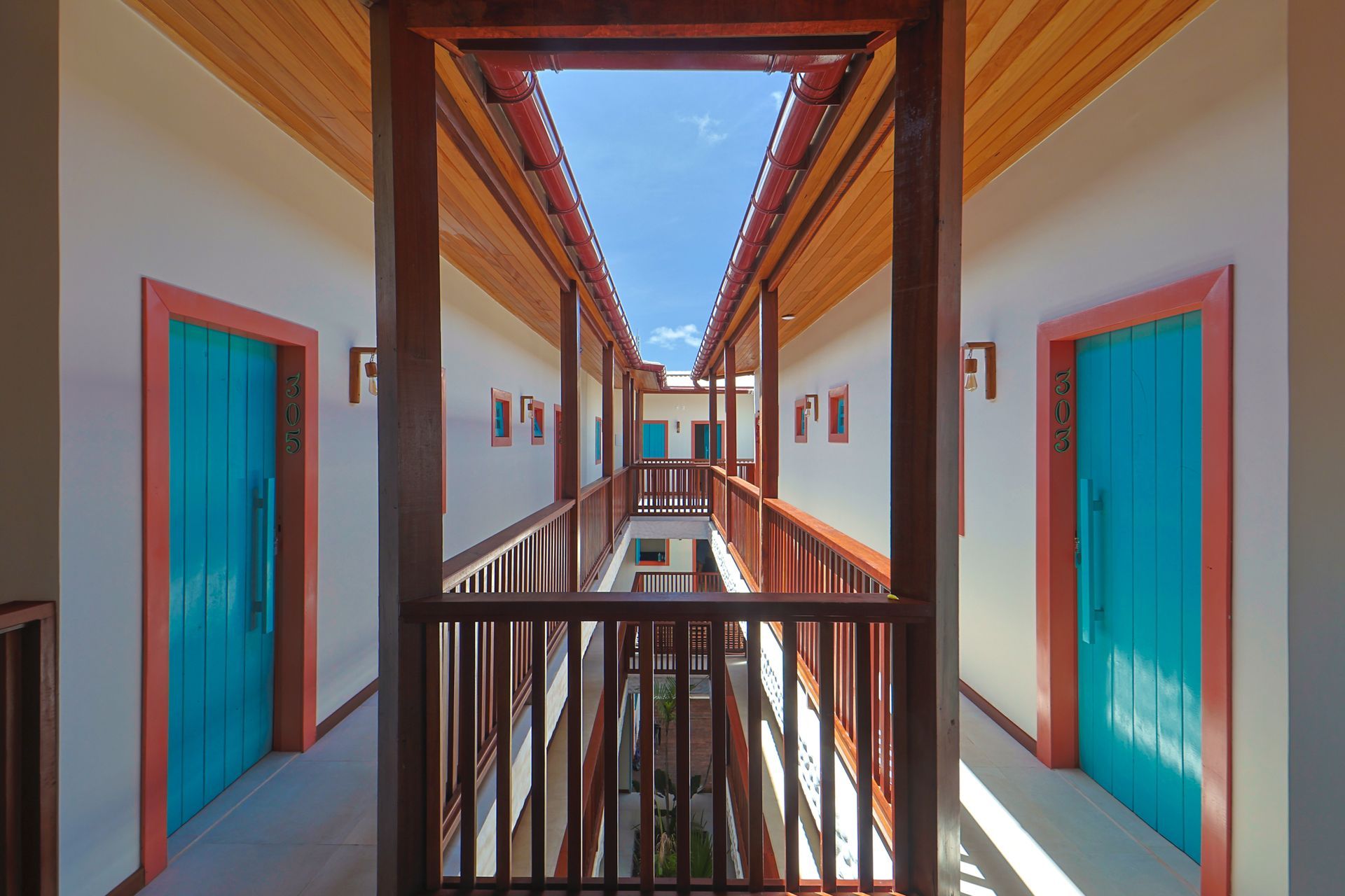 Um longo corredor com portas azuis e detalhes vermelhos