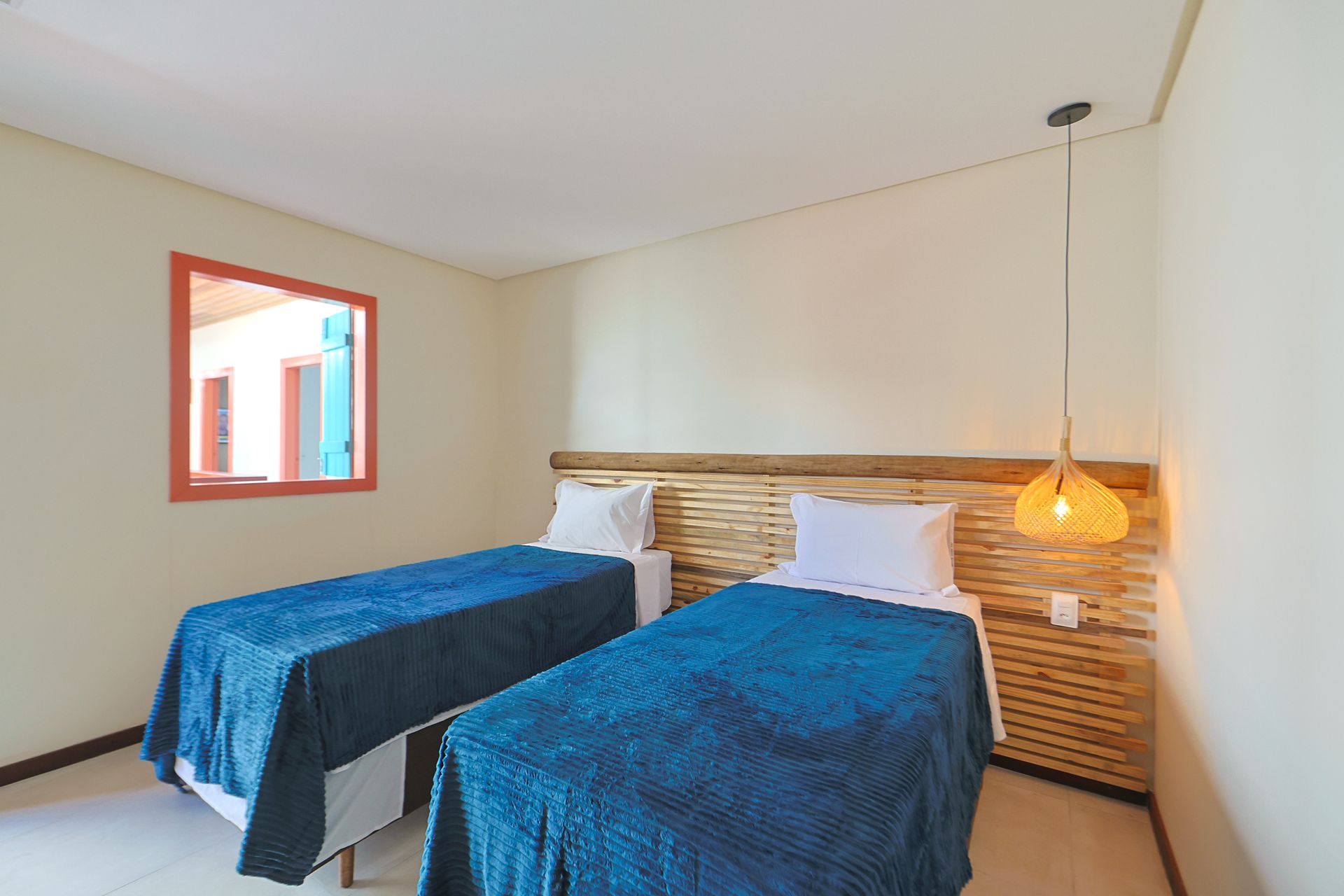 Um quarto com duas camas de solteiro e uma janela.