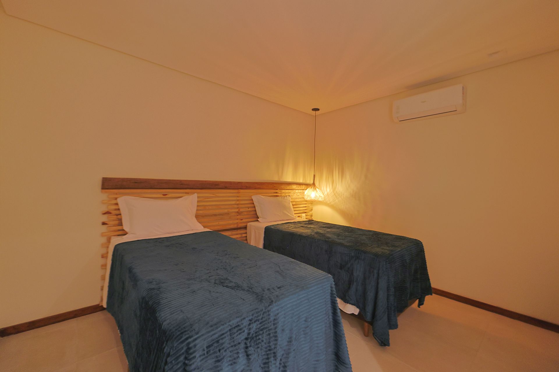 Um quarto com duas camas de solteiro e uma cabeceira de madeira.