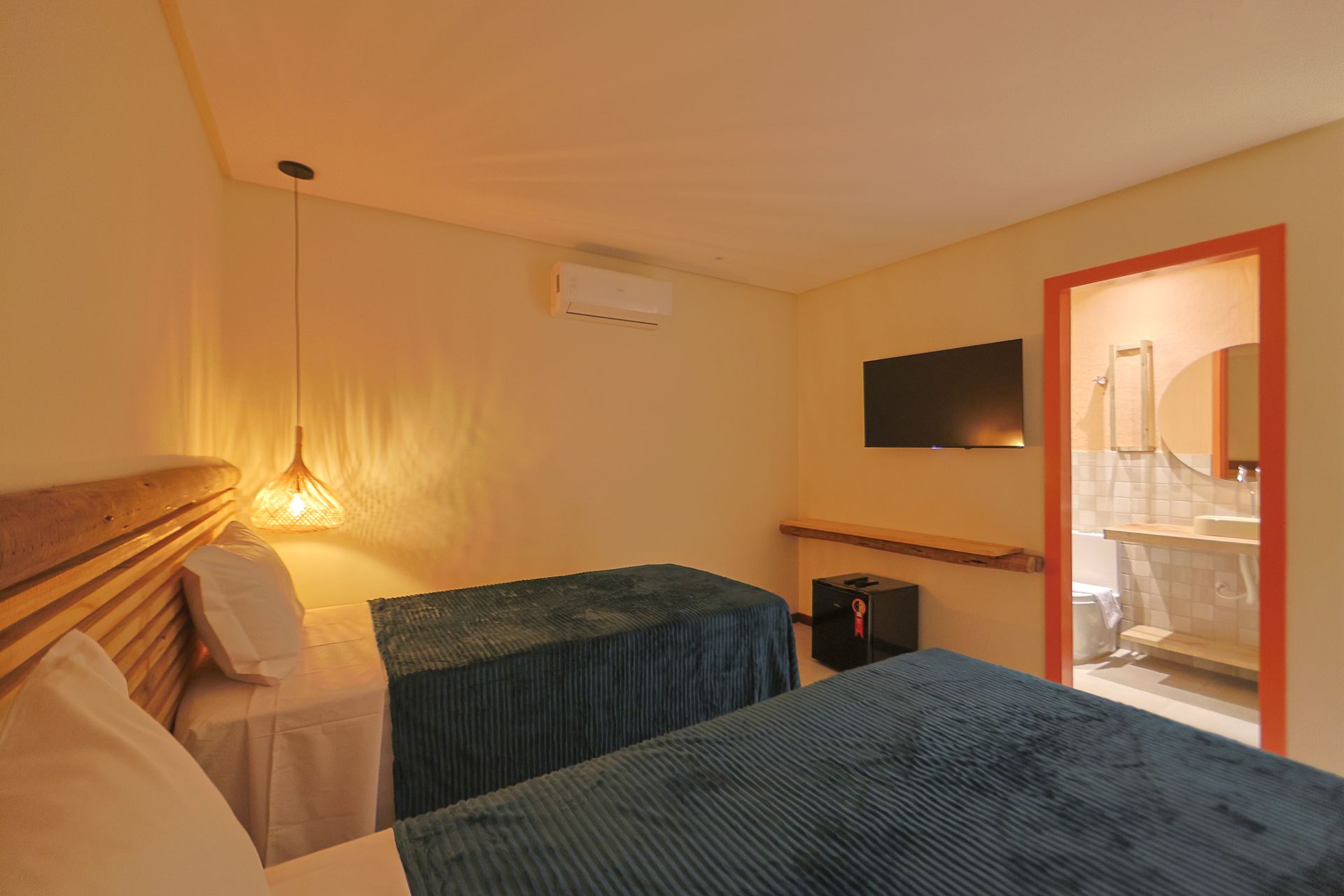 Um quarto de hotel com duas camas, uma televisão e um banheiro.