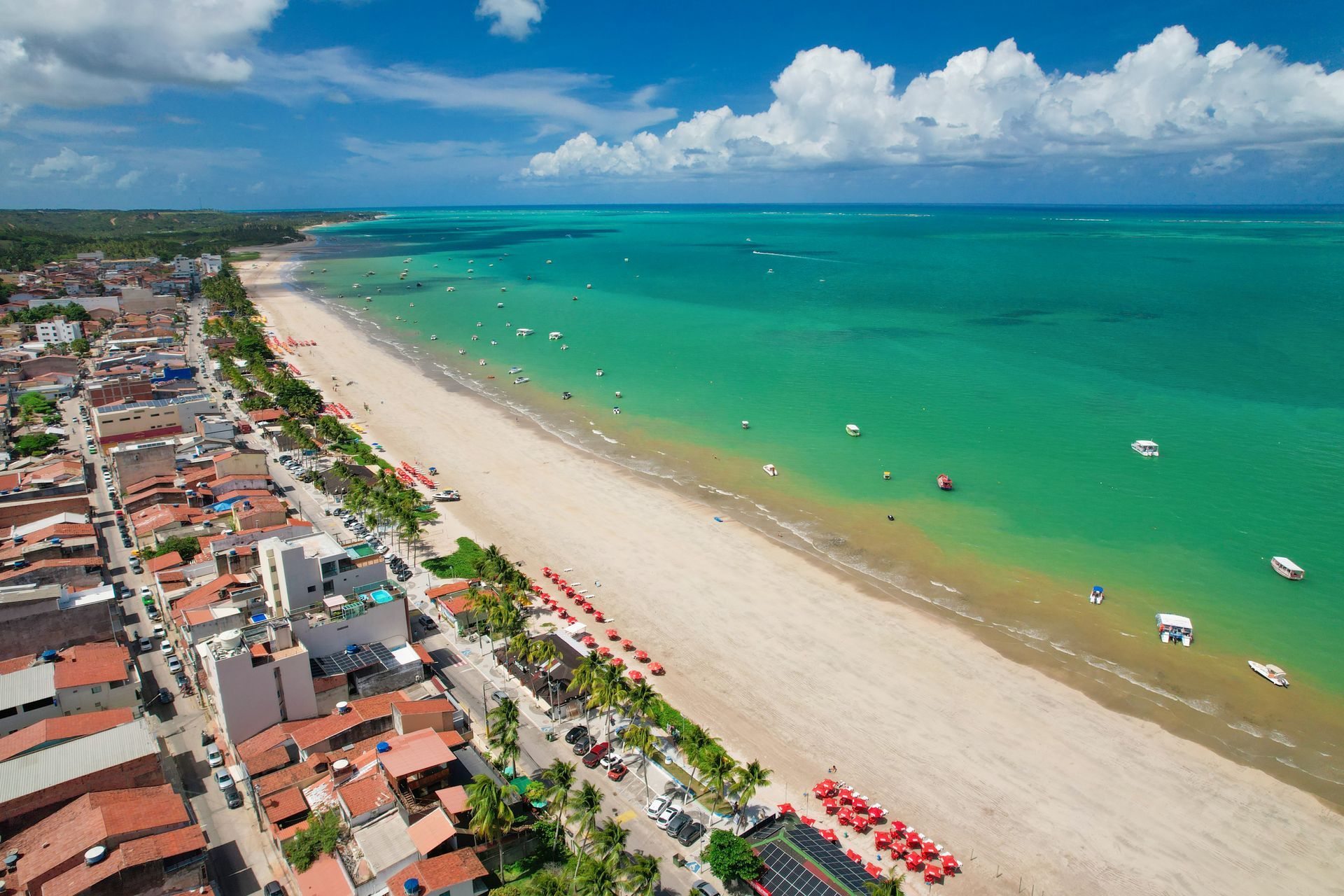 Uma vista aérea de uma praia com uma cidade ao fundo.
