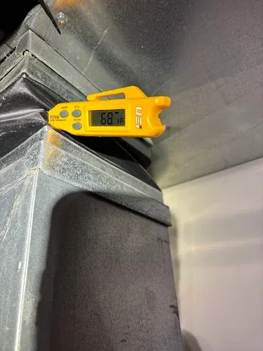 A yellow digital thermometer reads 68°F on an HVAC duct.