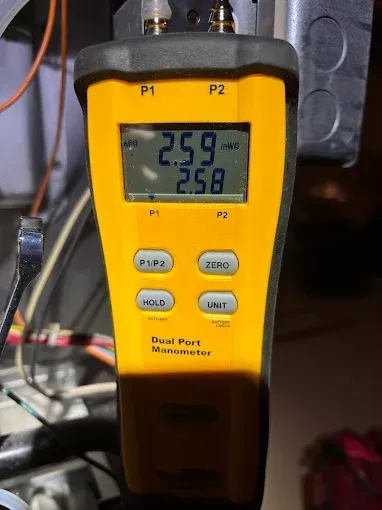 Yellow dual port manometer measuring gas pressure on a furnace. Readings are 2.59 and 2.58.