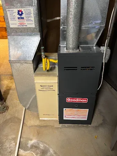 Furnace and air handler in a basement. Goodman furnace with gas line and ductwork.