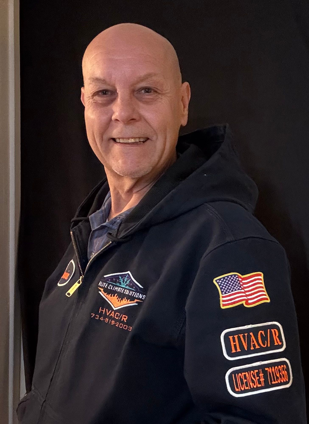 Marvin, a bald man, smiles in a blue work shirt, name stitched above pocket, and logo on sleeve.