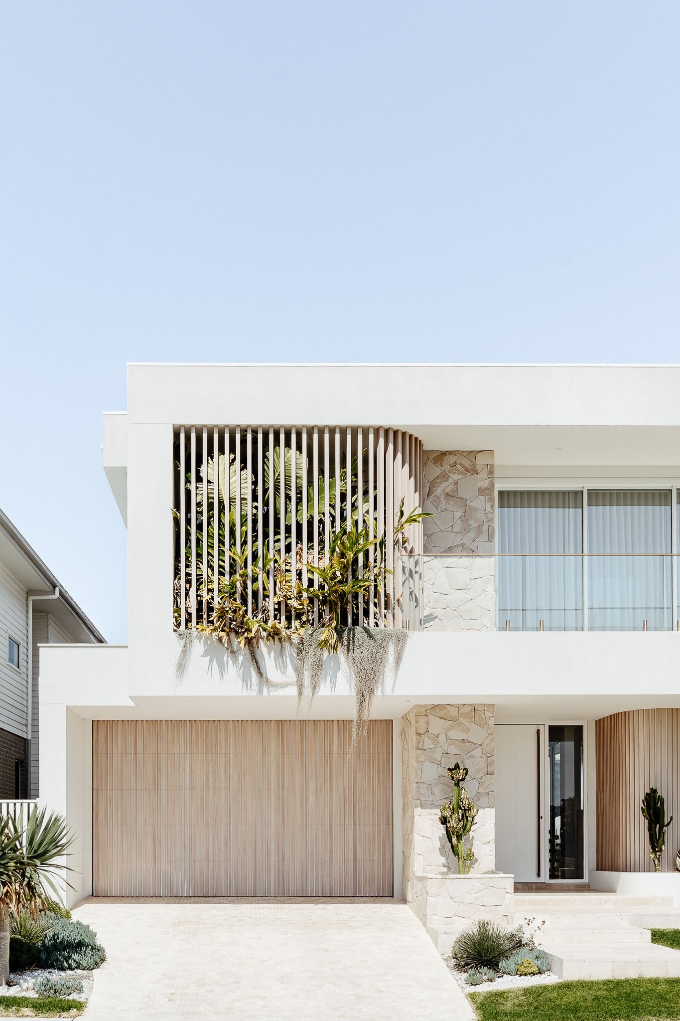 Modern white house with wooden accents and greenery, under a clear sky — SDC Building Design In Wollongong, NSW