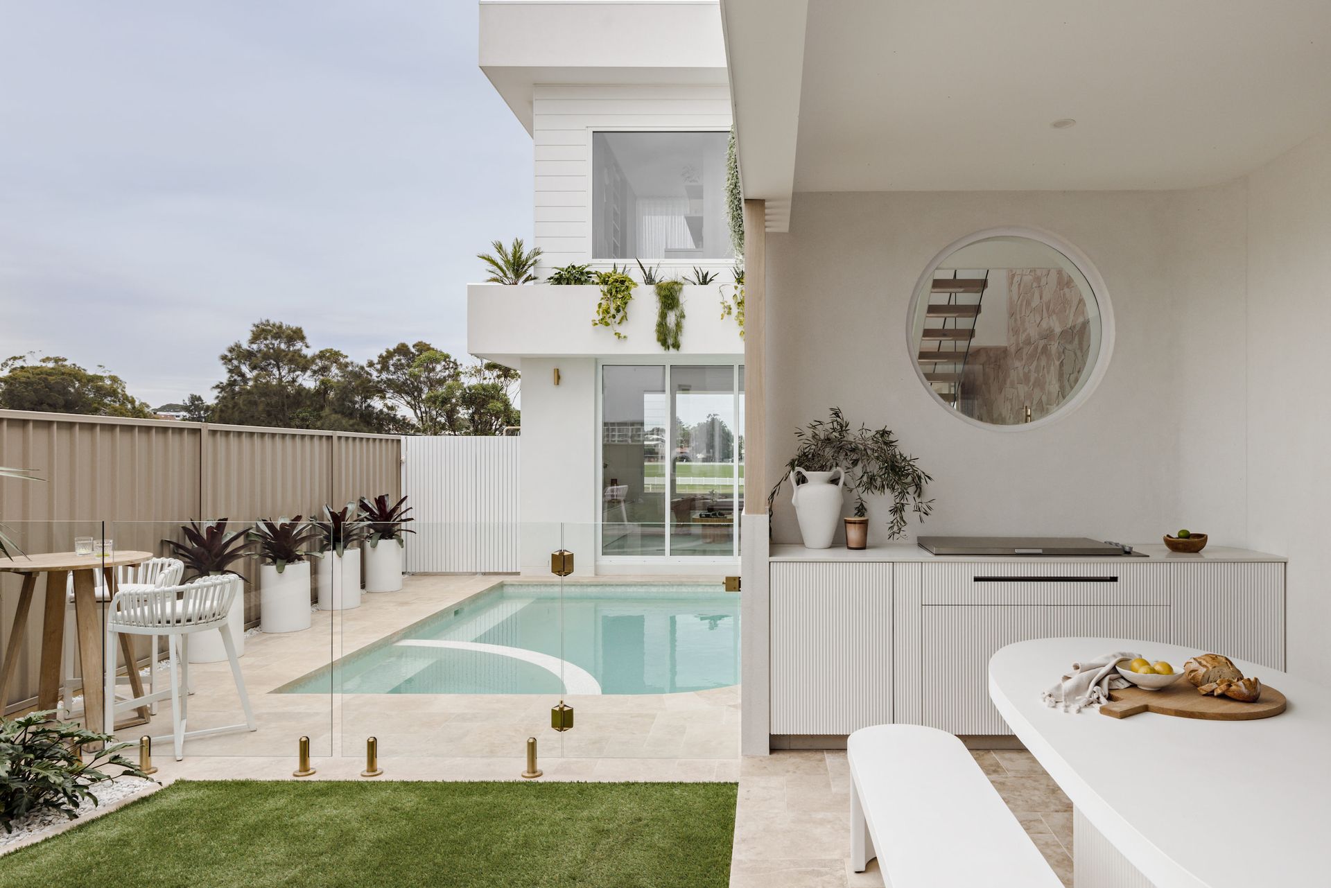 Backyard with pool, outdoor kitchen, and white modern house — SDC Building Design In Kiama, NSW