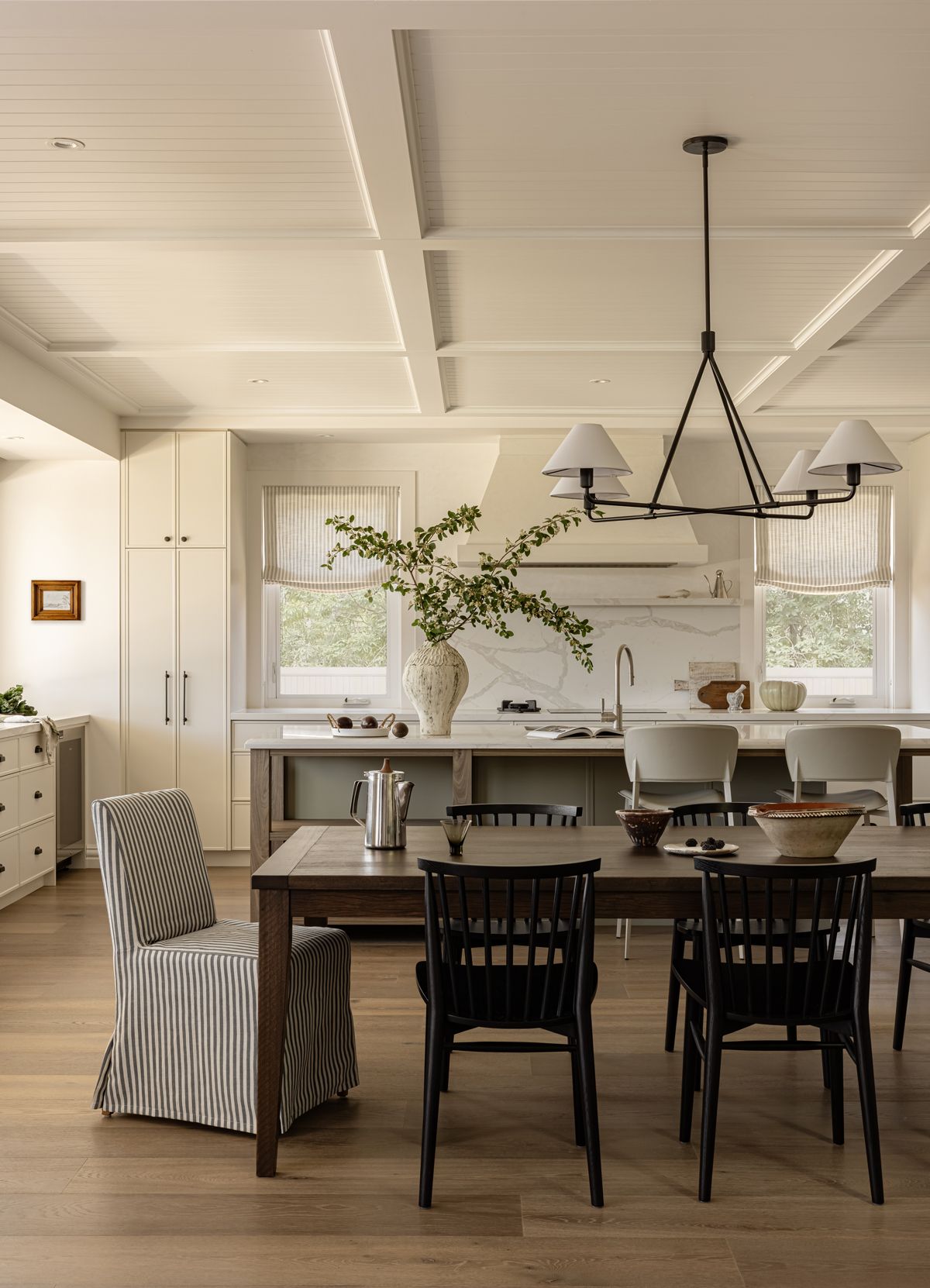 Dining room with a long wood table, chairs, and kitchen in the background. Natural light fills the space — SDC Building Design In Wollongong, NSW