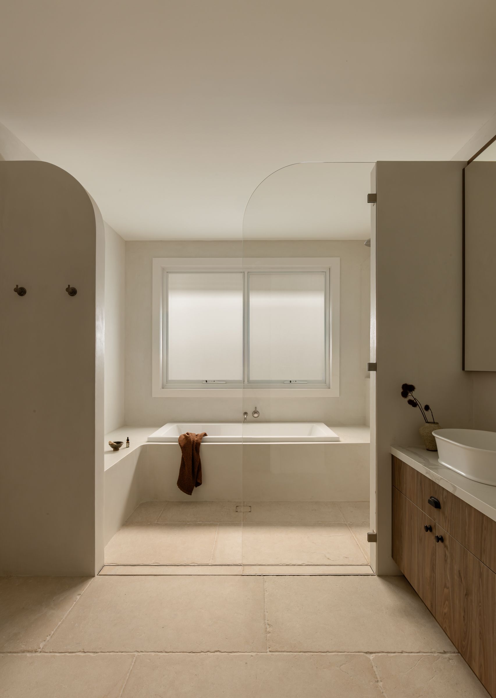 Bathroom With a Built-in Tub, Light Stone Tiling, and a Frosted Window — SDC Building Design In Kiama, NSW