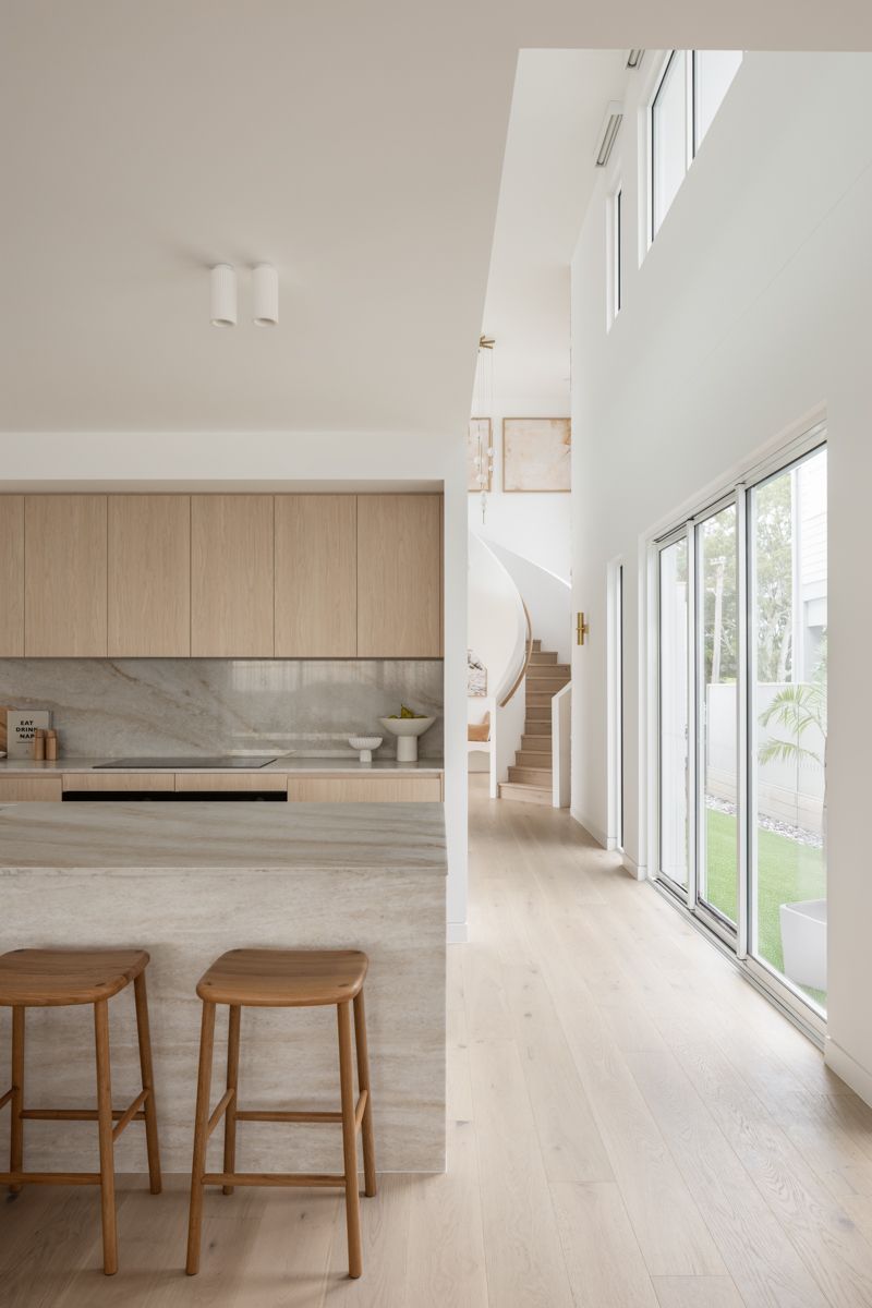 Modern kitchen and hallway with light wood cabinetry, stone island, and stairs. — SDC Building Design In Kiama, NSW